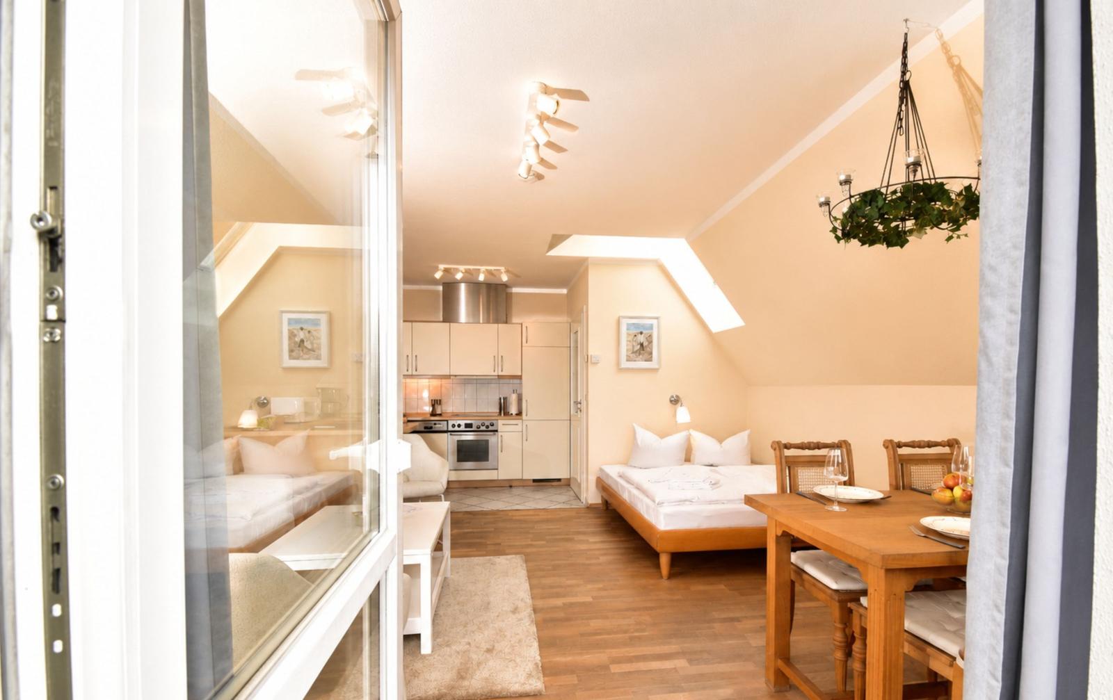 Ein Schlafzimmer mit Bett, Esstisch und Küche unter einer Dachschräge.