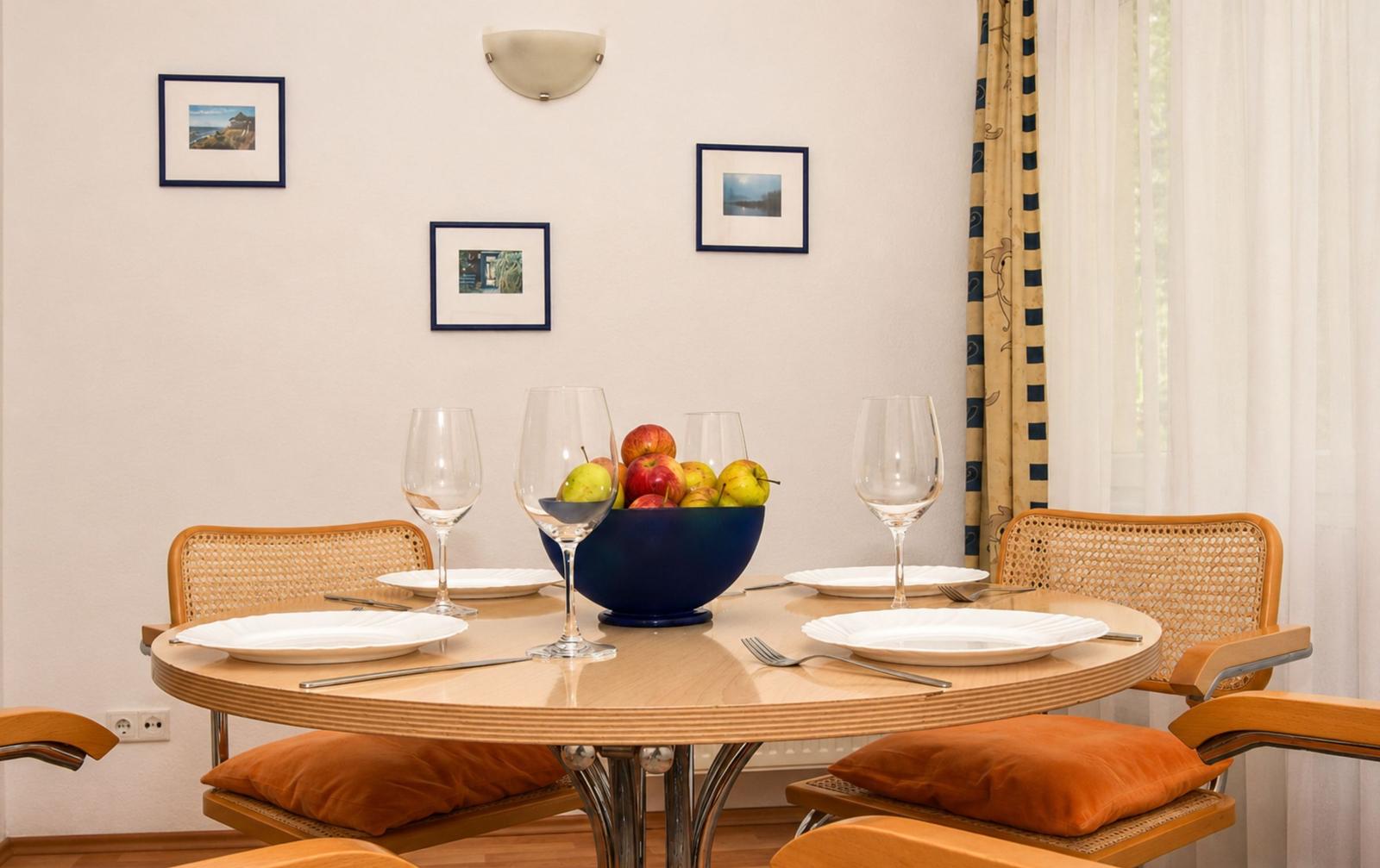 Rundes Esszimmer mit Tisch, Stühlen und Obstschale.