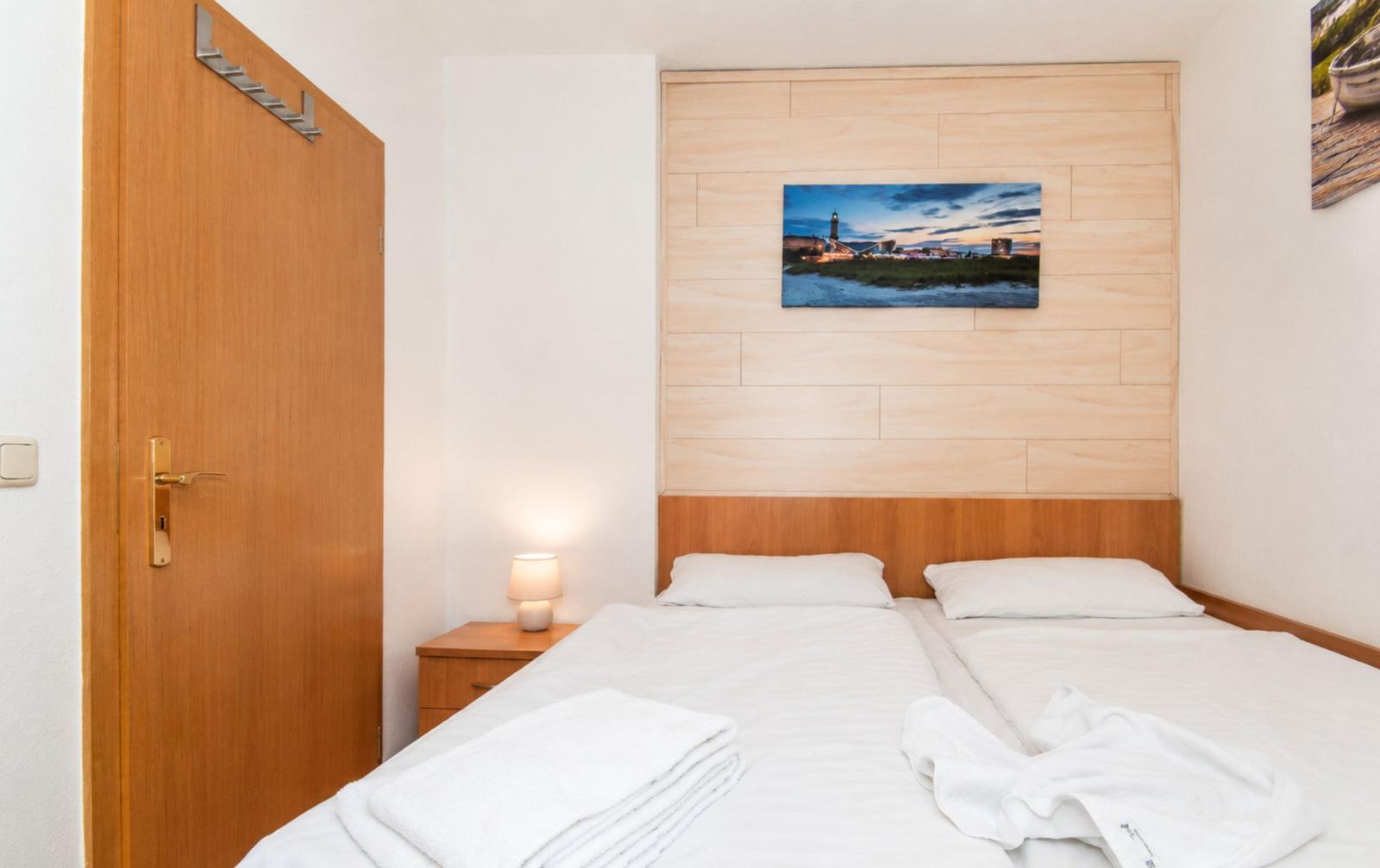 Schlafzimmer mit Doppelbett, Holzwand und Nachttisch mit Lampe.