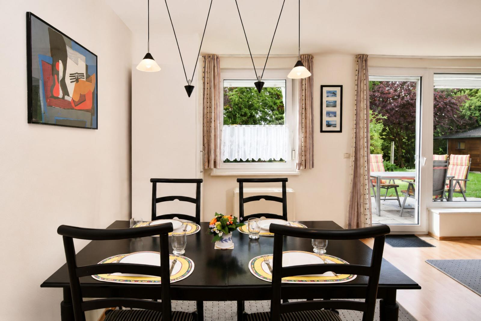 Esszimmer mit Tisch, Stühlen und Fenster zum Garten.