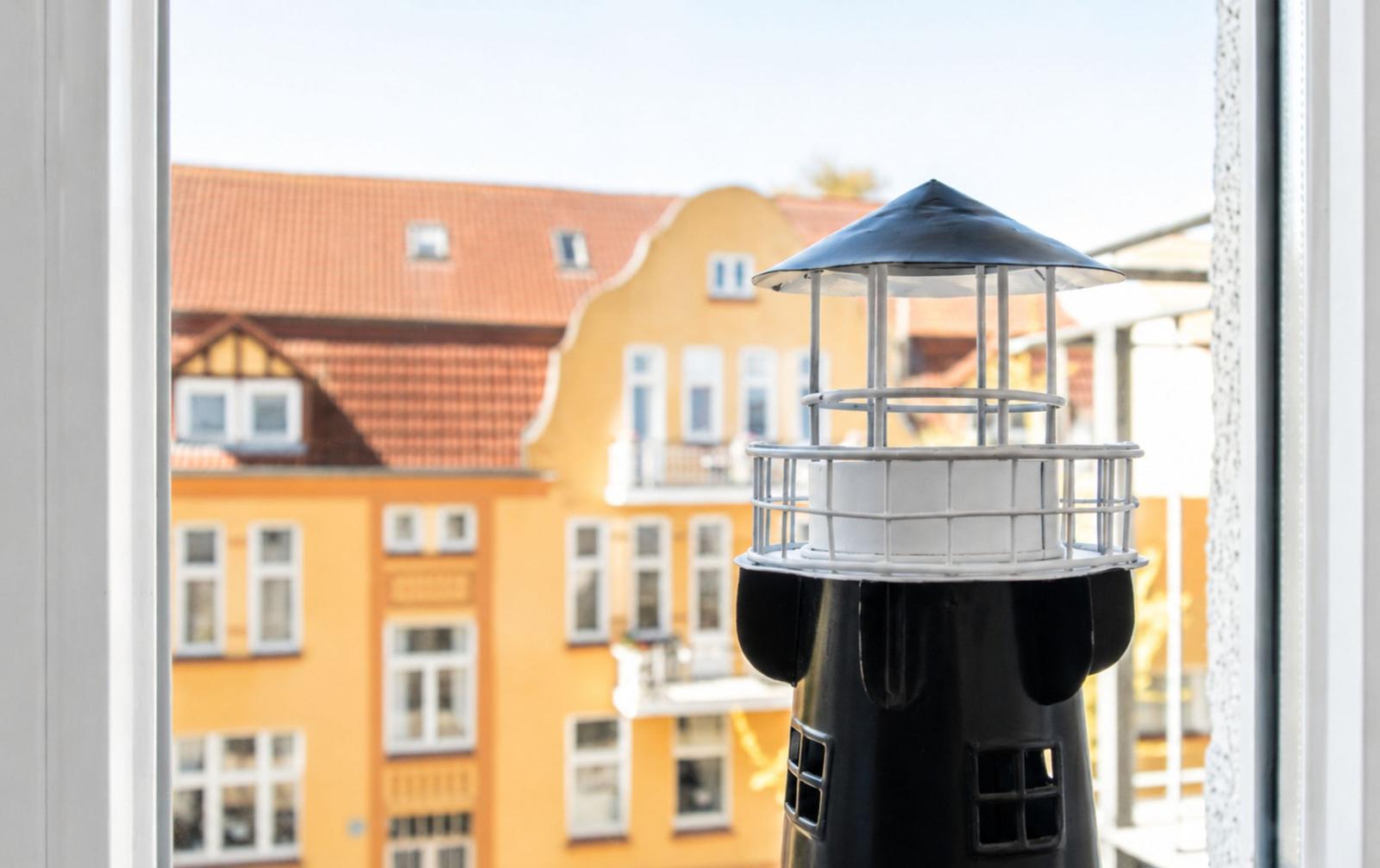 Mini lighthouse on windowsill with view of yellow building