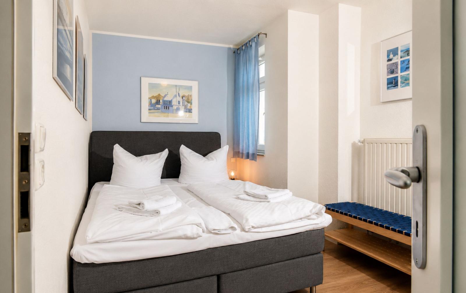 Bedroom with double bed, blue curtains, and wall pictures.