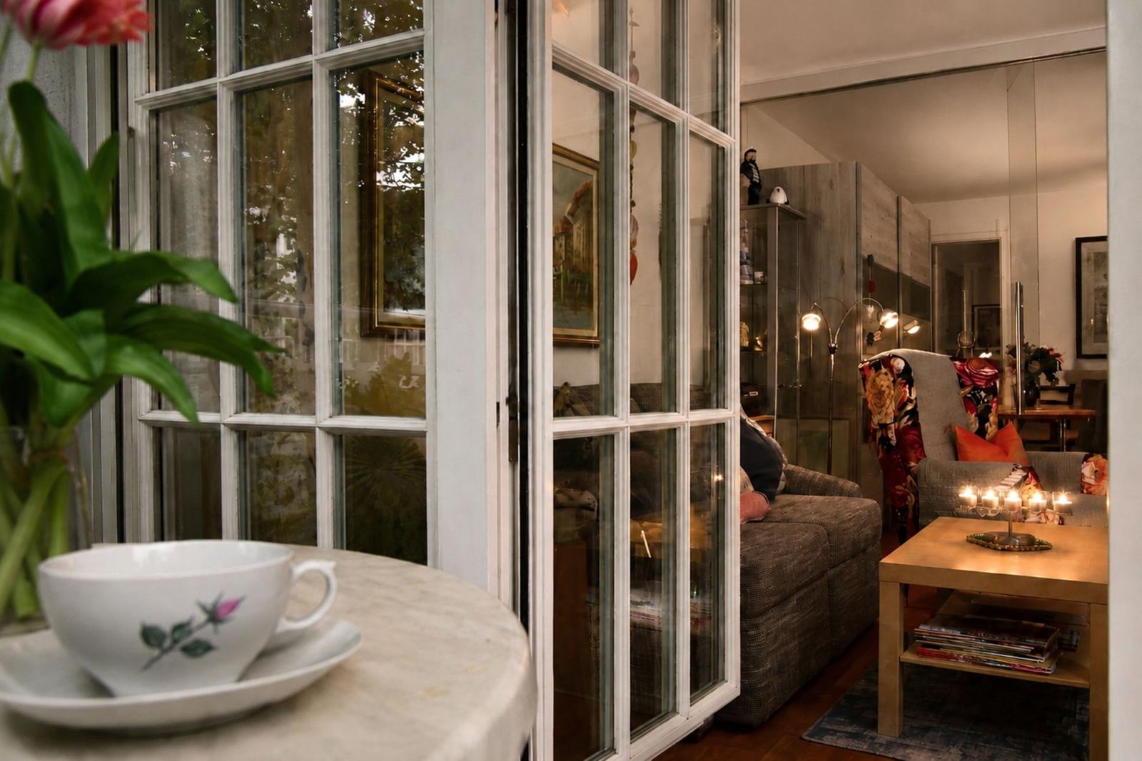 A room with a window, a table with a cup, and a sofa in the background.