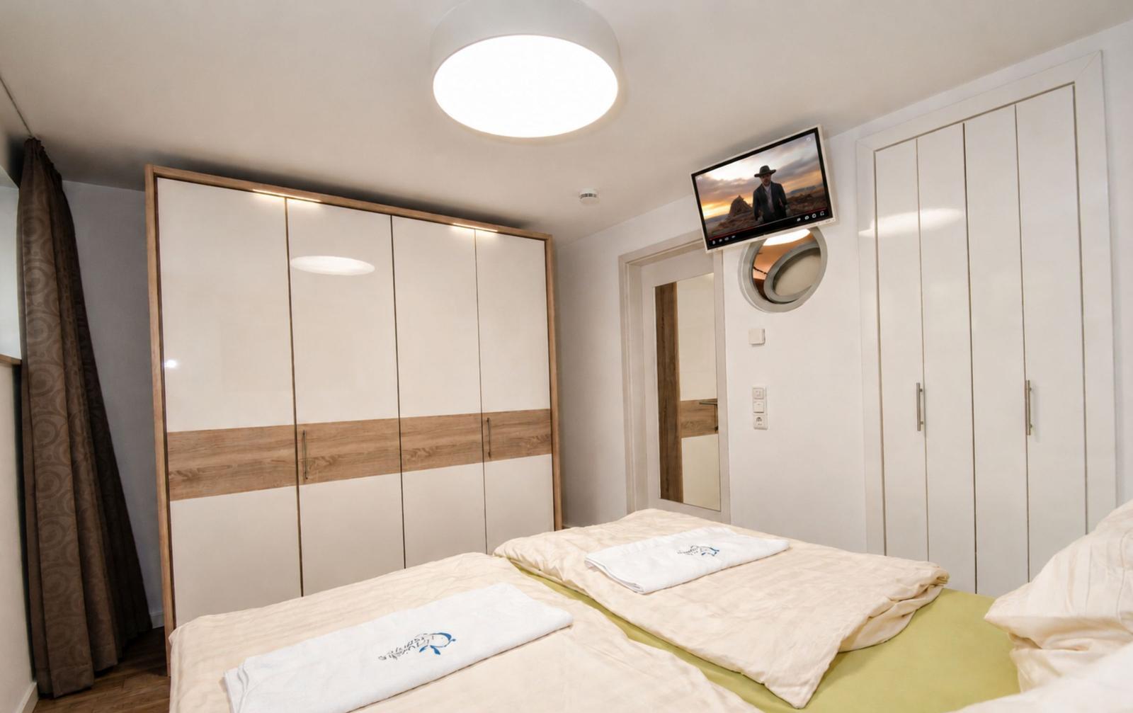 Schlafzimmer mit Doppelbett, Kleiderschrank und Wand-TV.