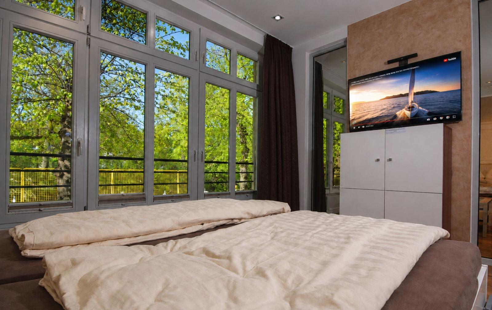 Schlafzimmer mit großem Fenster und TV an der Wand.