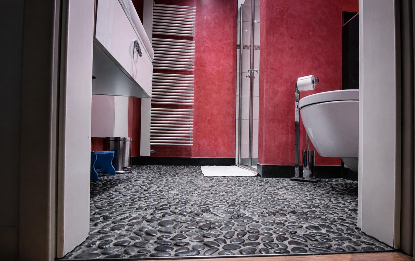 Badezimmer mit roten Wänden, Steinboden und Dusche