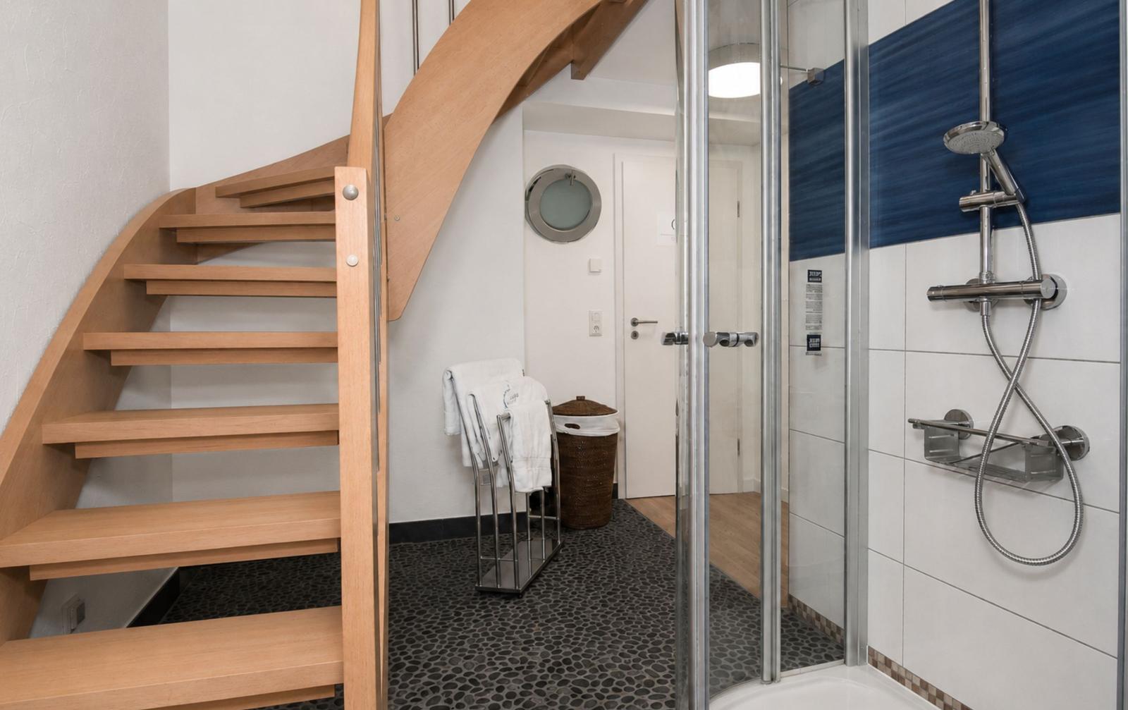 Dusche mit Glaswand, Holztreppe und Waschbeckenbereich