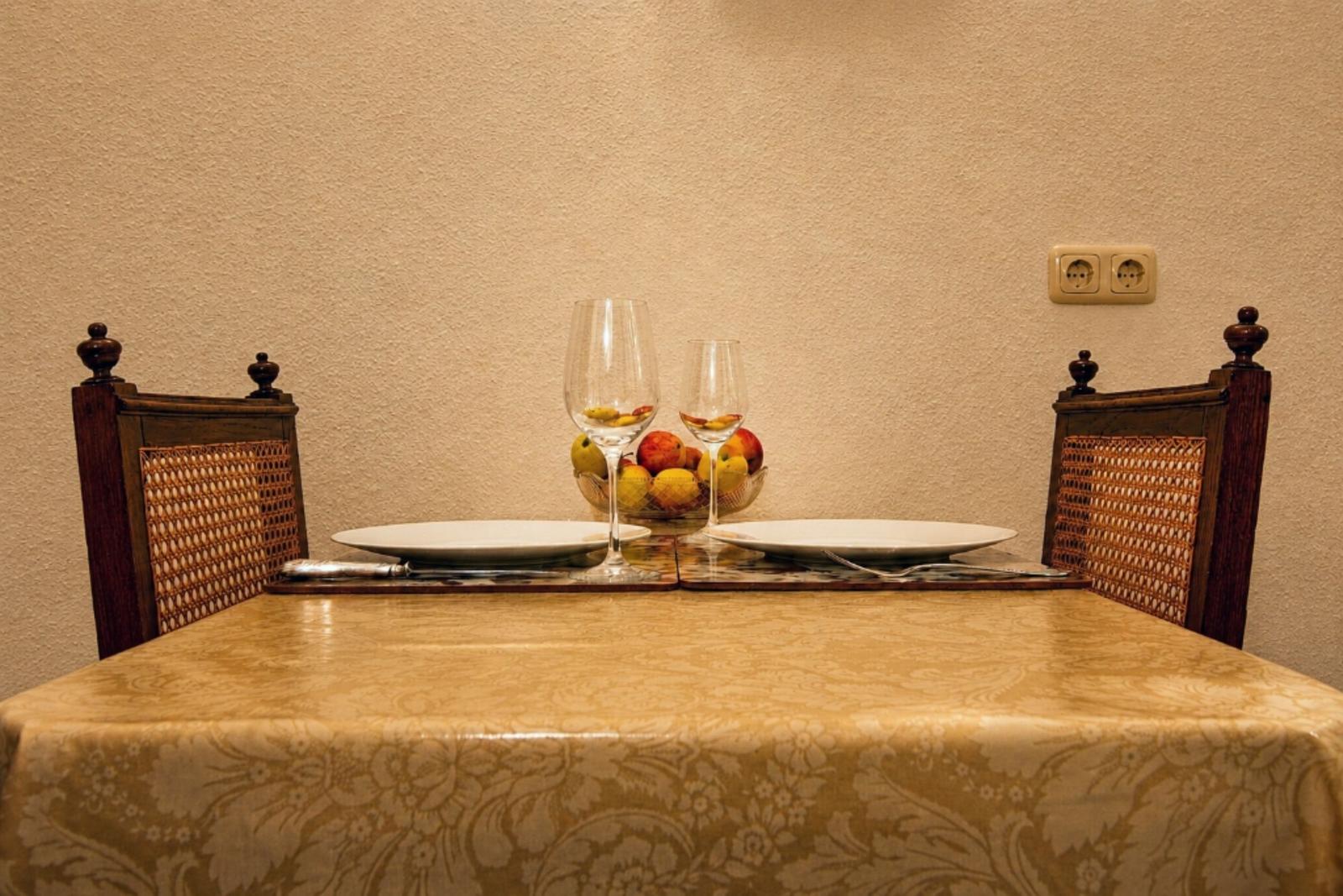 Tisch mit zwei Stühlen, Tischdecke, Gläser und Obstschale.