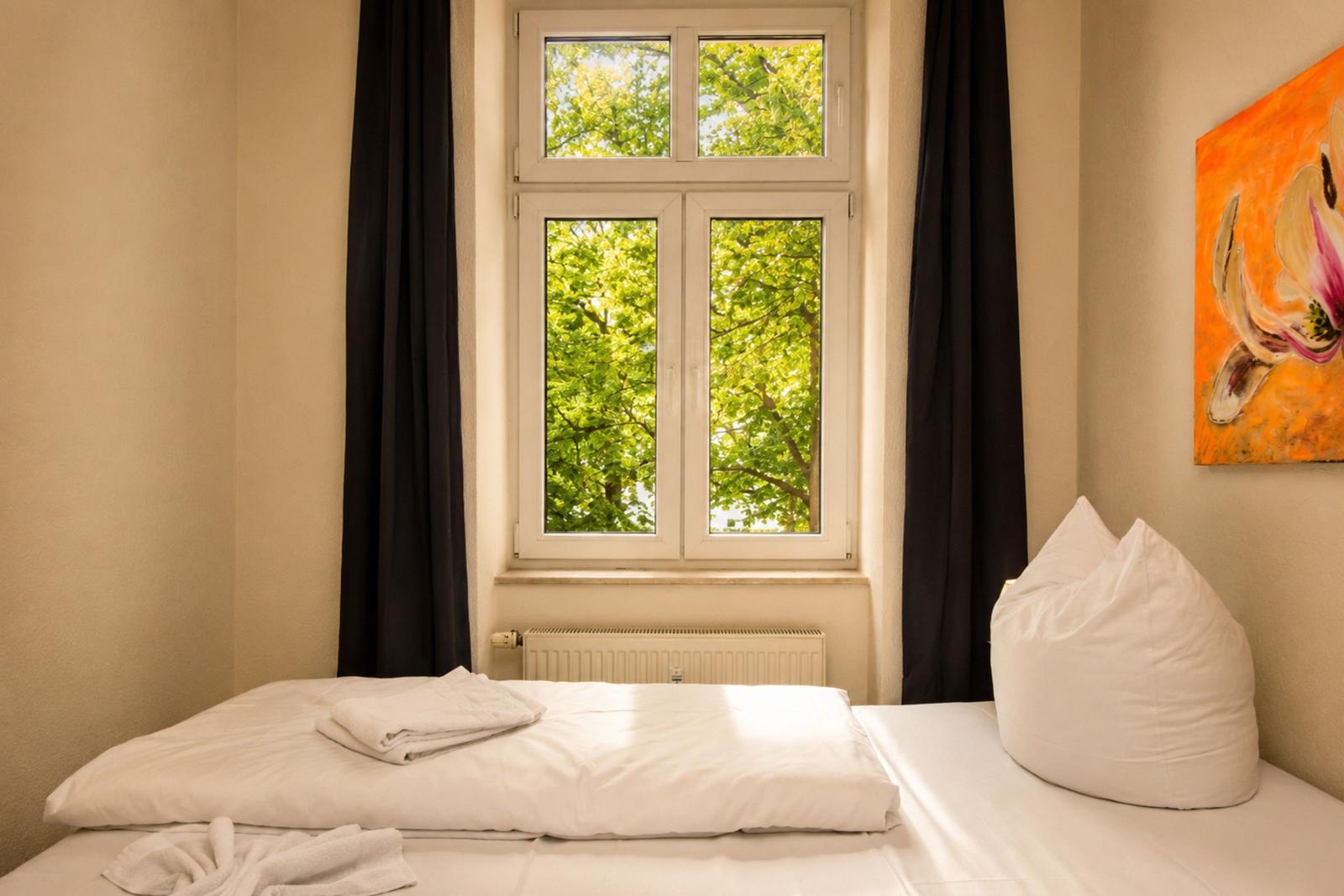 Schlafzimmer mit Bett, Fenster und Wandbild.