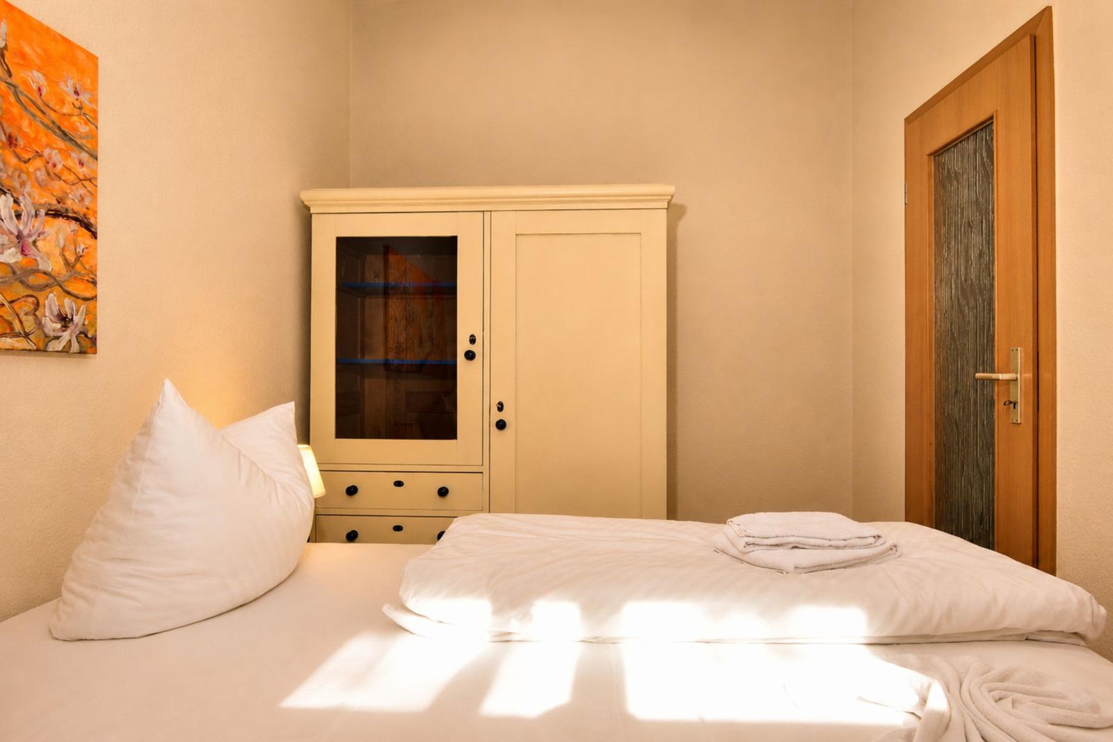 Schlafzimmer mit Bett, Kleiderschrank und Wandbild.