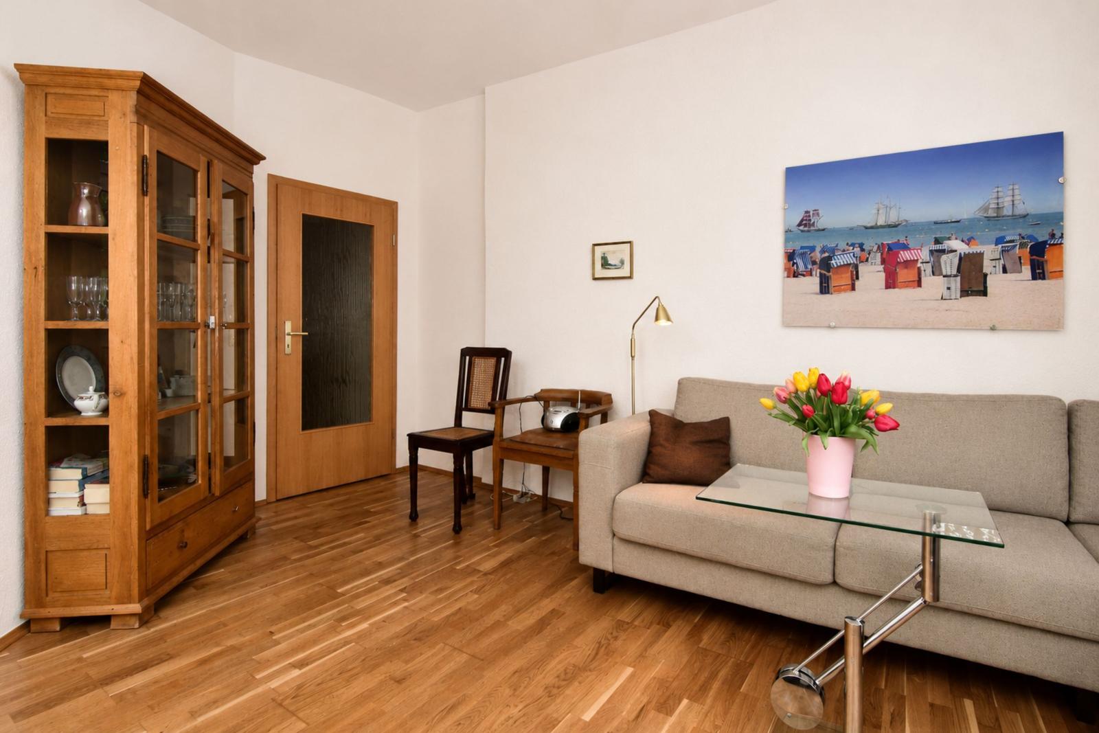Wohnzimmer mit Sofa, Glas-Tisch, Holzfußboden und Bild an der Wand.