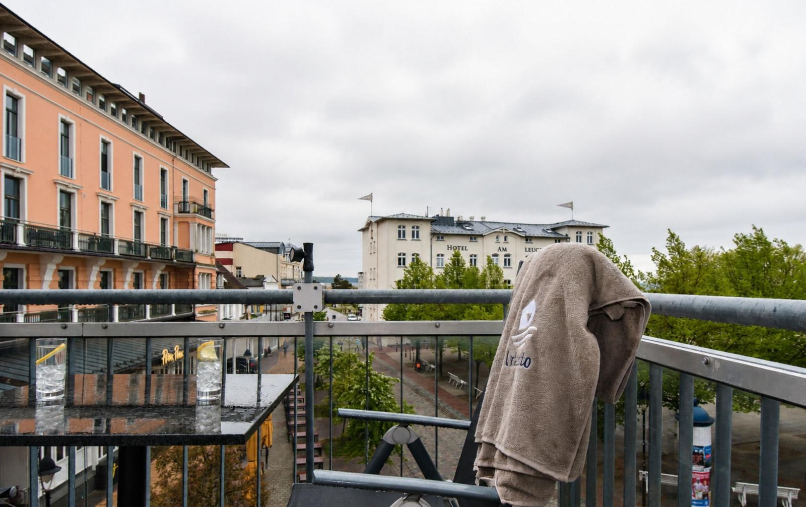 Balkon mit Blick auf Hotel und Straße. Handtuch hängt am Geländer.