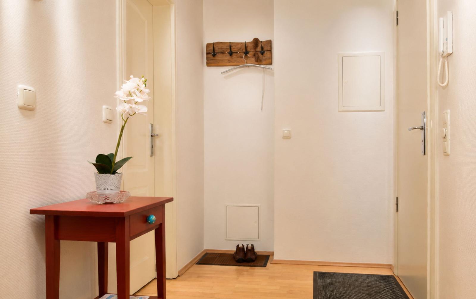 Eingangsbereich mit Holztisch, Orchidee, Kleiderhaken und Schuhtrenner