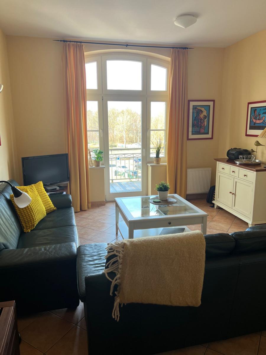 Wohnzimmer mit Sofa, Glas-Tisch und Blick auf Balkon