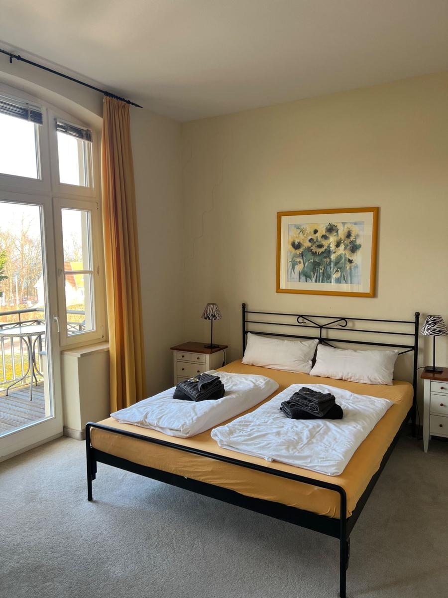 Schlafzimmer mit Doppelbett, Fenster und Bild an der Wand.