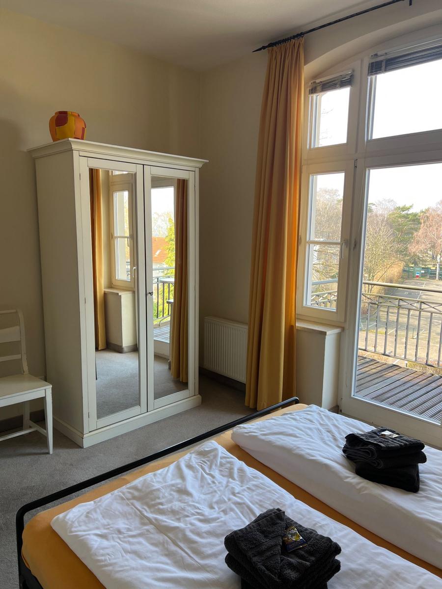 Zimmer mit zwei Betten, Spiegelschrank und Balkon mit Blick auf Außenbereich.