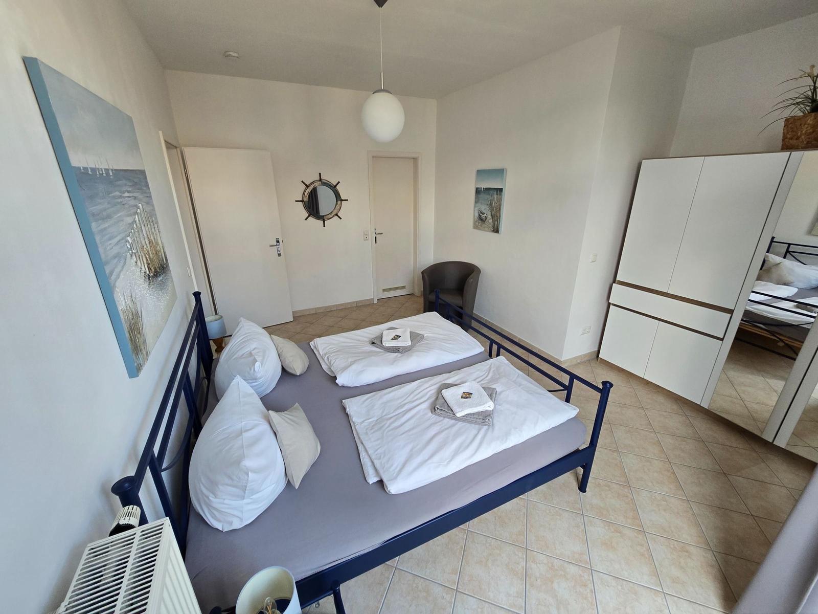 Schlafzimmer mit Doppelbett, Kleiderschrank und Wandbildern