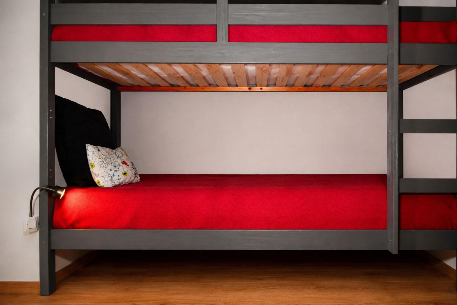 Ein Doppelstockbett mit roter Bettwäsche und einem Kissen.
