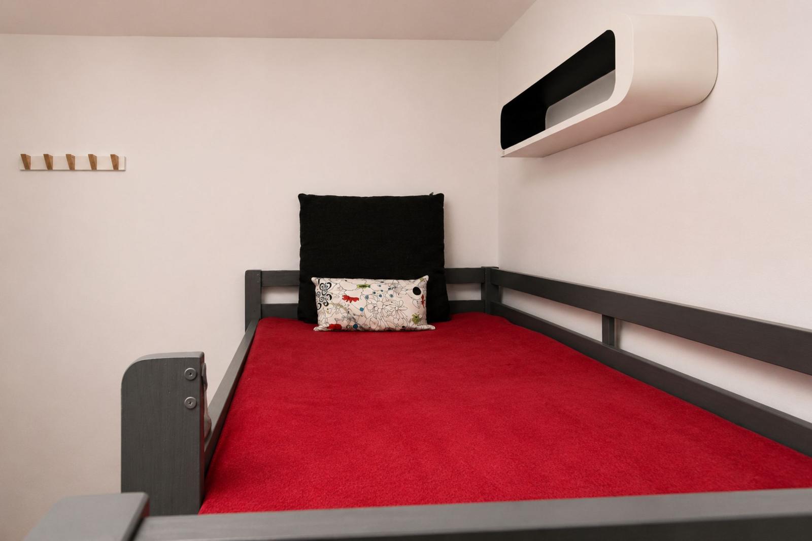 Ein Bett mit rotem Teppich und Kissen an der Wand