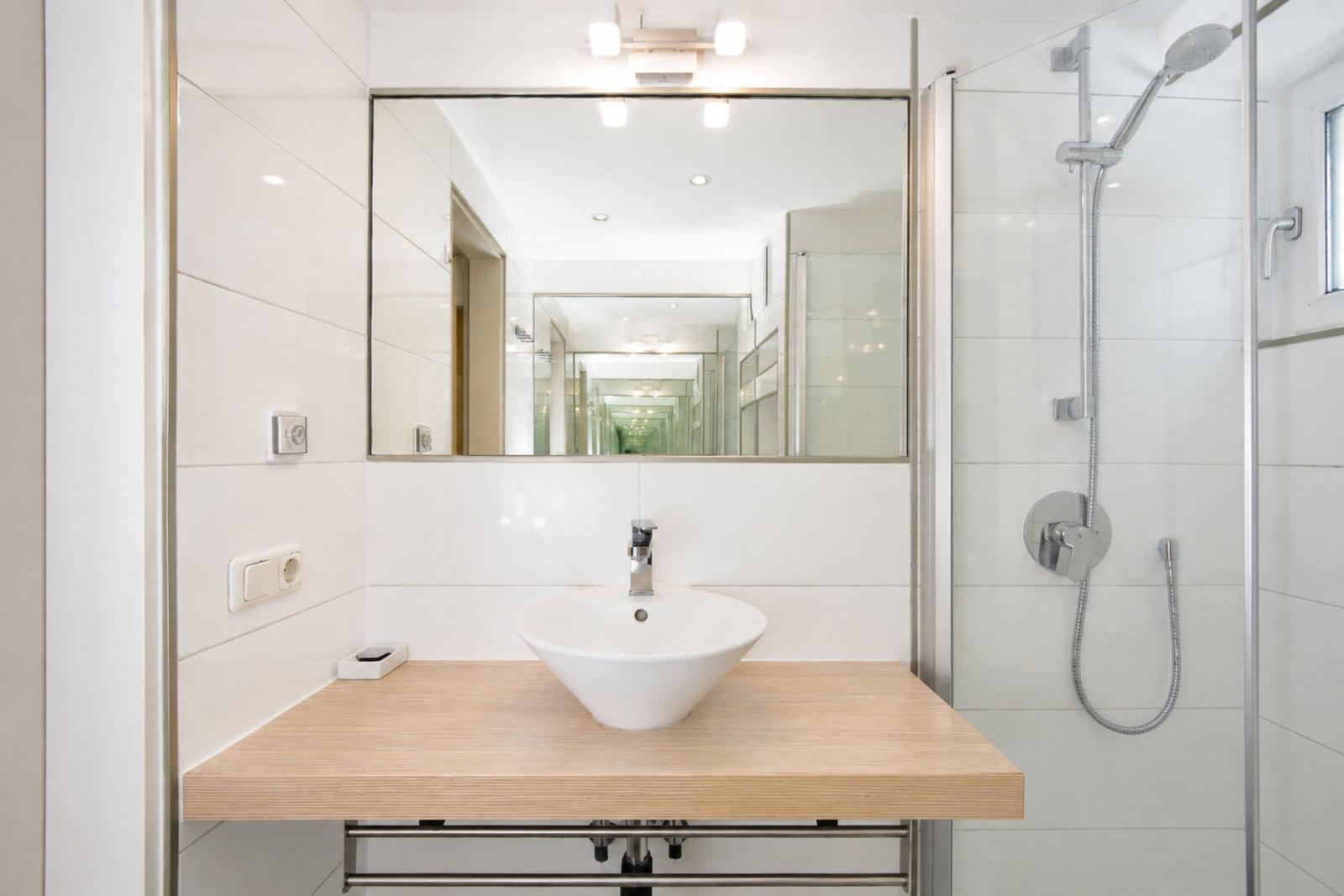 Badezimmer mit Dusche, Waschbecken und Spiegel