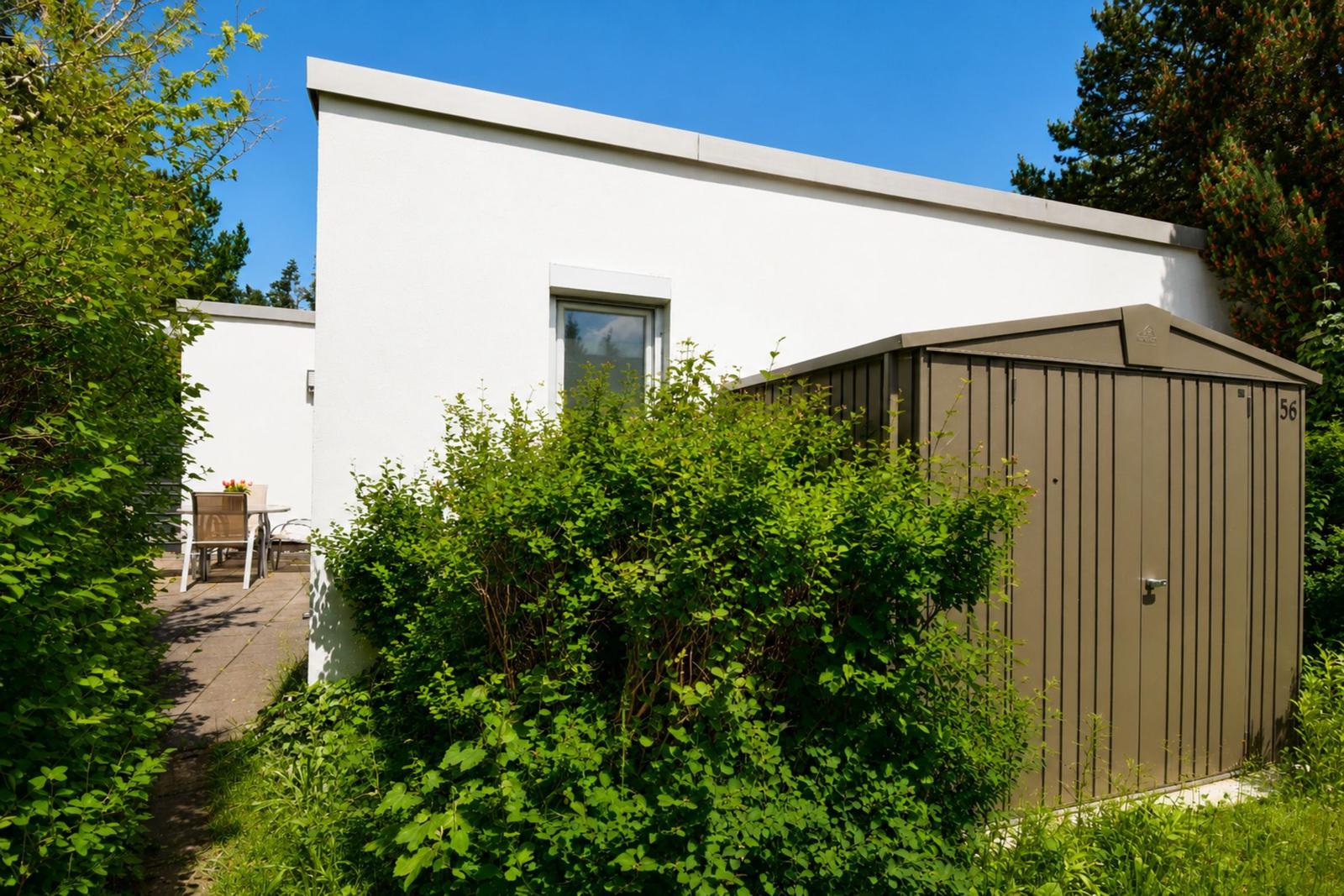 Wohnung mit Garten, Terrasse und Gartenhaus. Umgeben von grüner Vegetation.