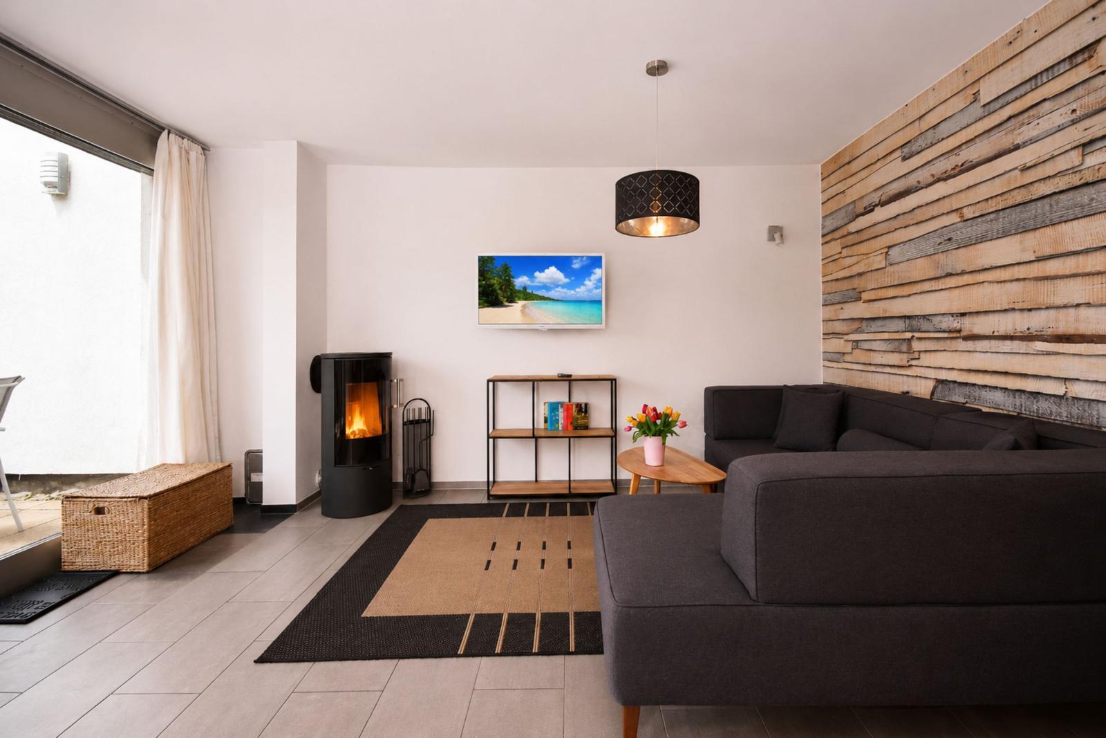 Wohnzimmer mit Sofa, Kamin und Holzwand