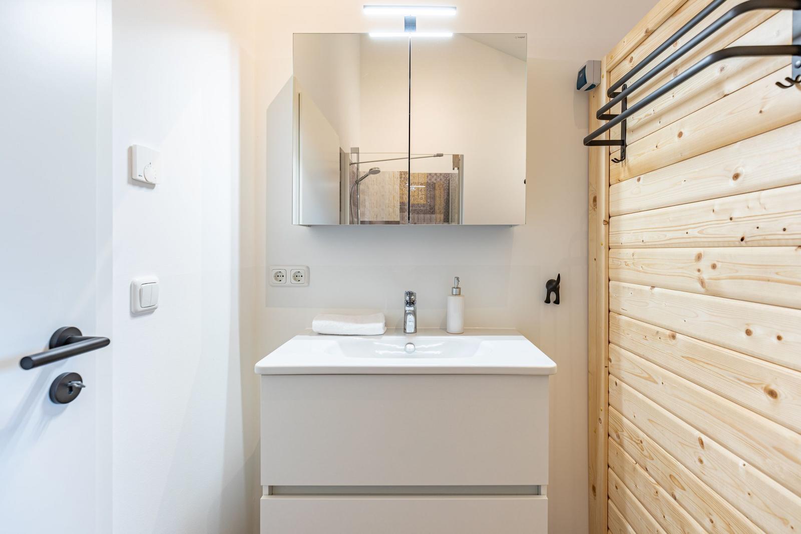 Badezimmer mit Waschbecken, Spiegel und Holzwand