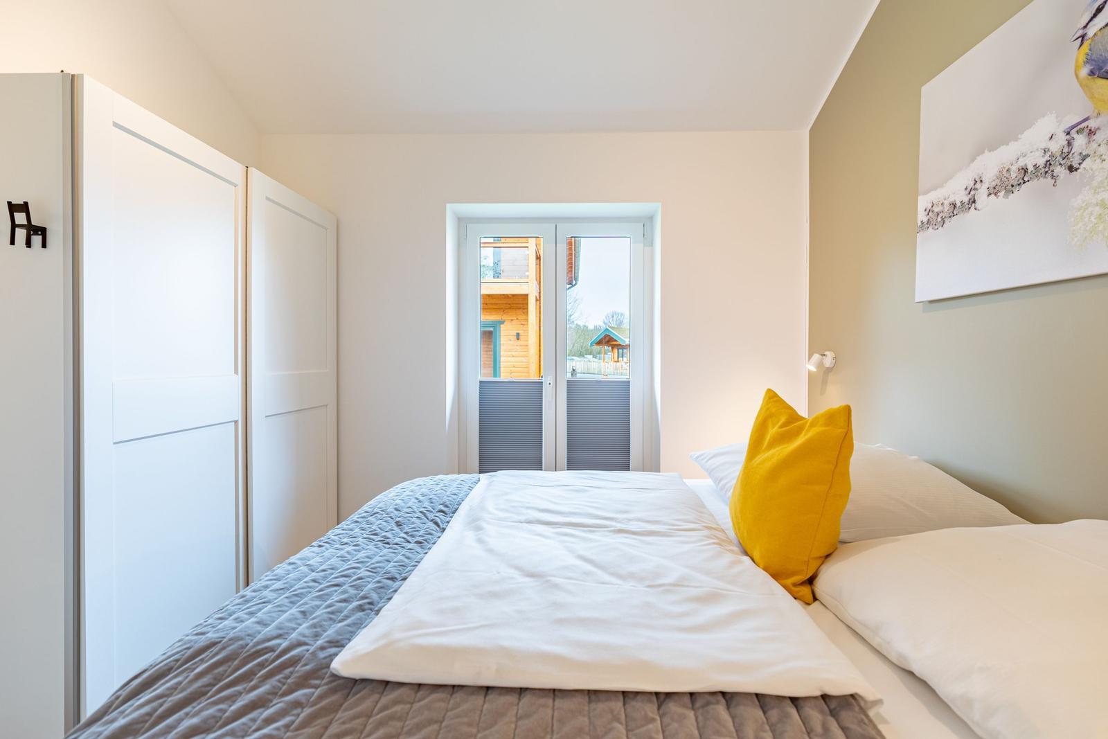 Schlafzimmer mit Bett, Schrank und Blick auf Außenbereich.