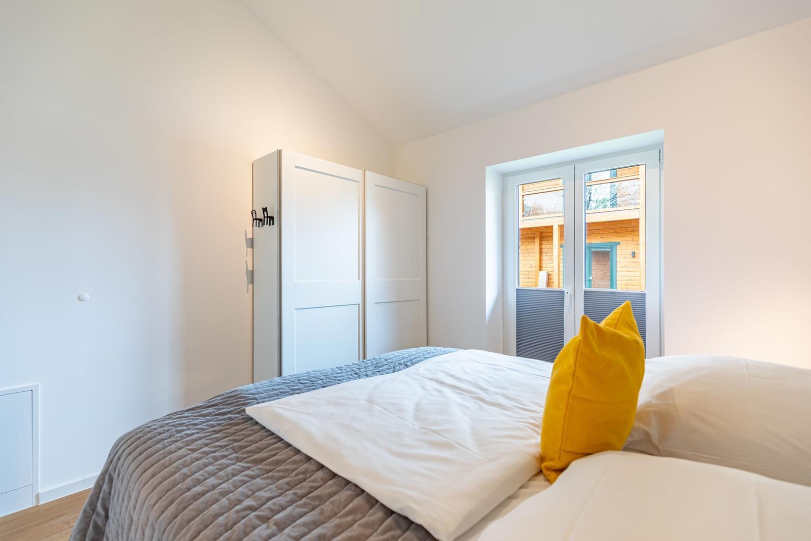 Schlafzimmer mit Bett, Schrank und Fenster zur Außenseite.