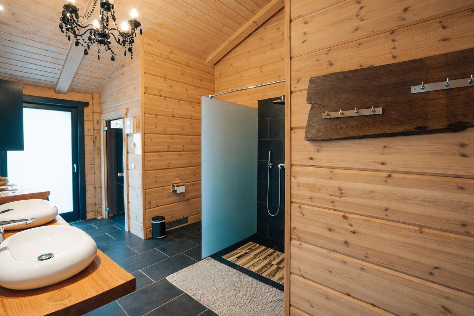 Badezimmer mit Holzwand, Dusche und Waschtisch