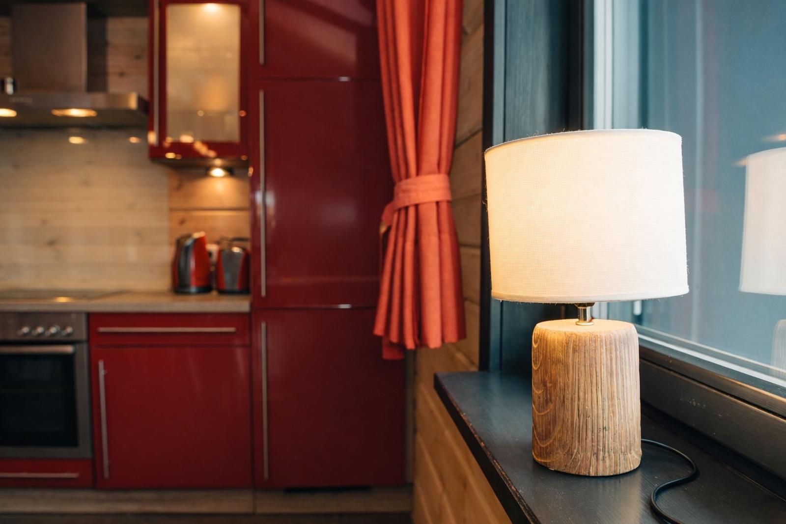 Lampe auf Fensterbank neben roter Küchenzeile mit Holzwand