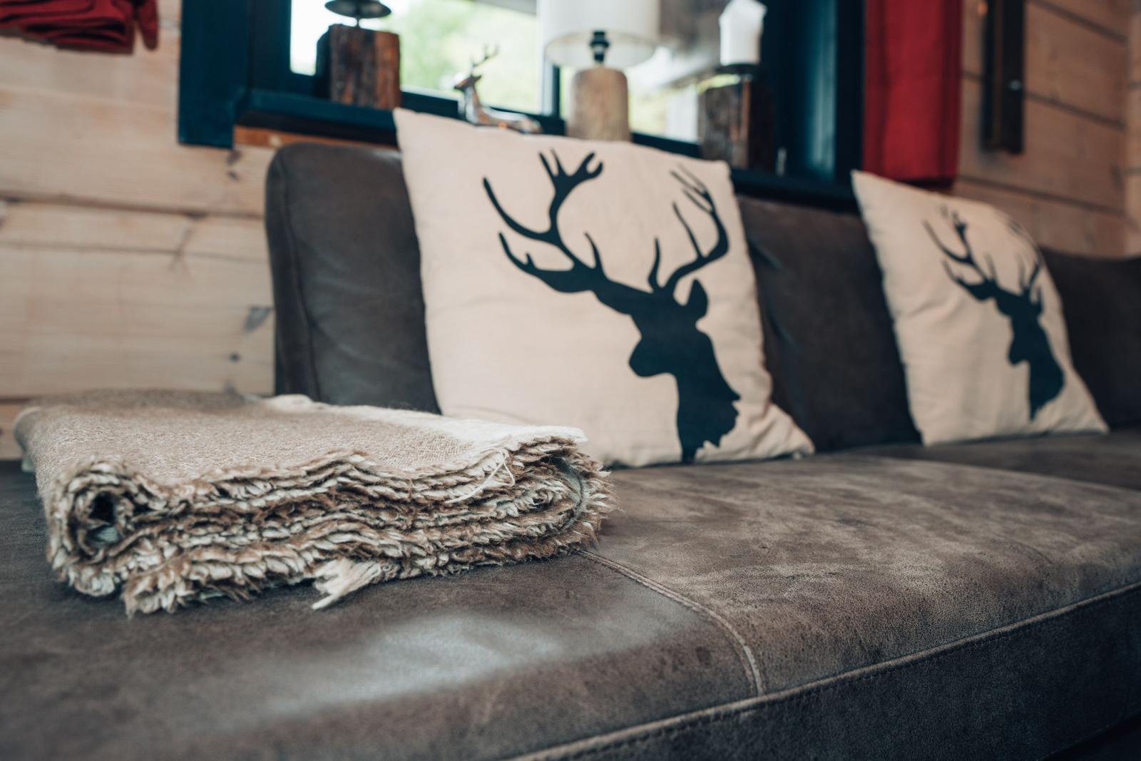 Ein Sofa mit Kissen in Form von Hirschköpfen und einer Decke.