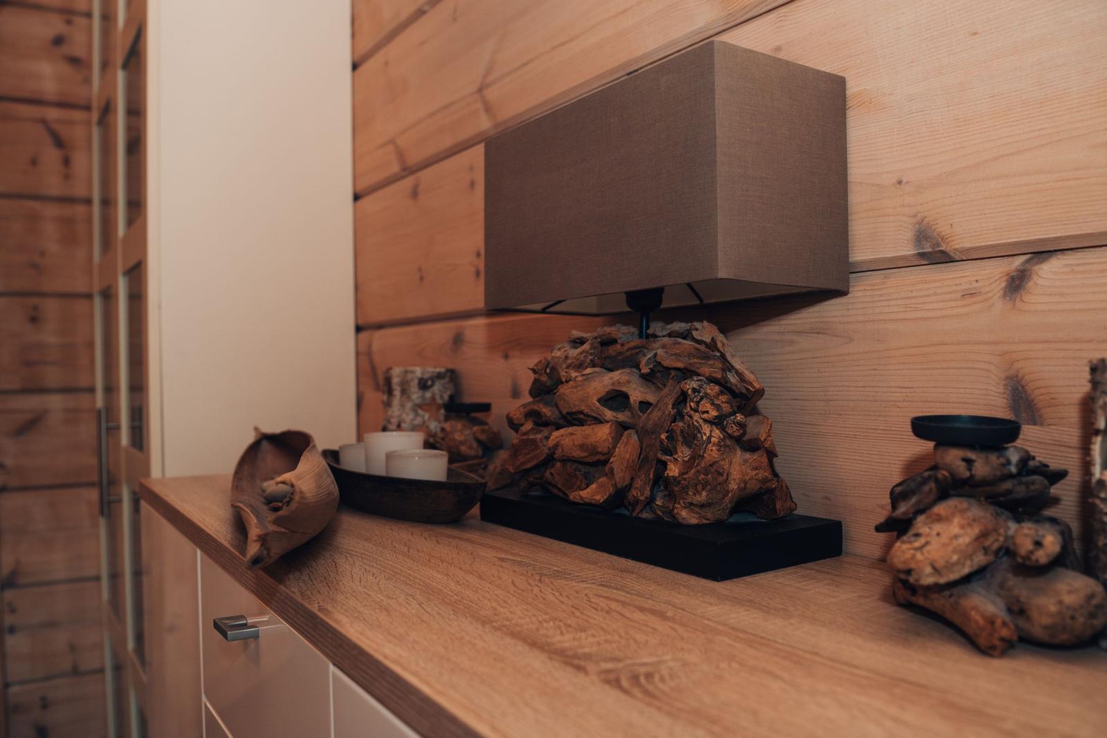 Holzregal mit Lampe, Steine und Kerzen auf dunkler Basis