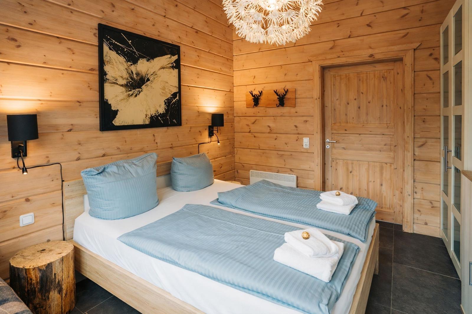 Schlafzimmer mit Holzwand, Doppelbett, Decken und Handtüchern.