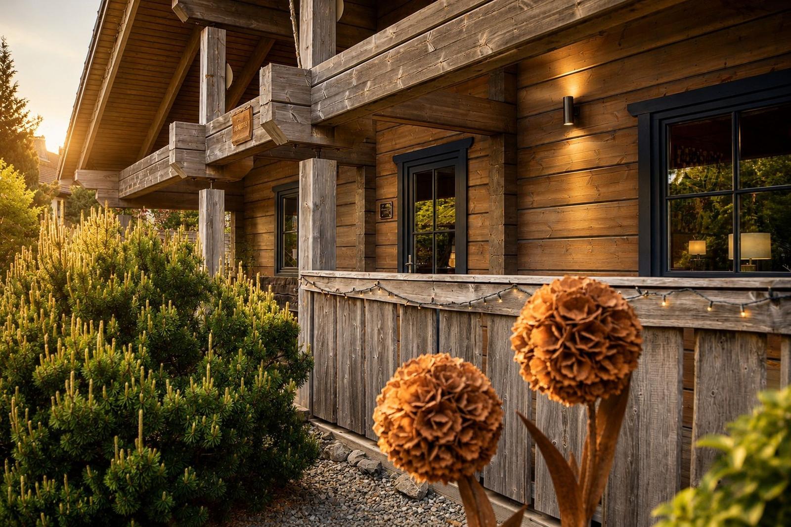 Holzhaus mit Balkon, Fenstern und dekorativen Pflanzen im Vorgarten.