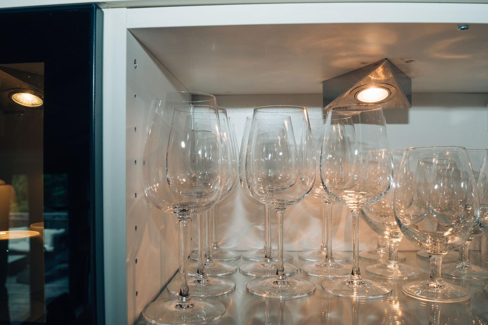 Mehrere Weingläser stehen in einem Schrank mit integrierter Beleuchtung.