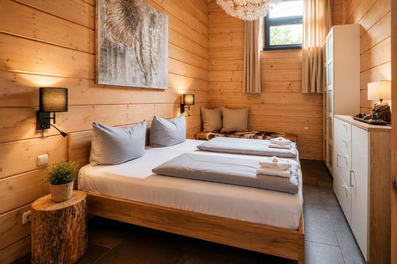 Ein Schlafzimmer mit Holzwand, Bett, Schrank und Wandbild.