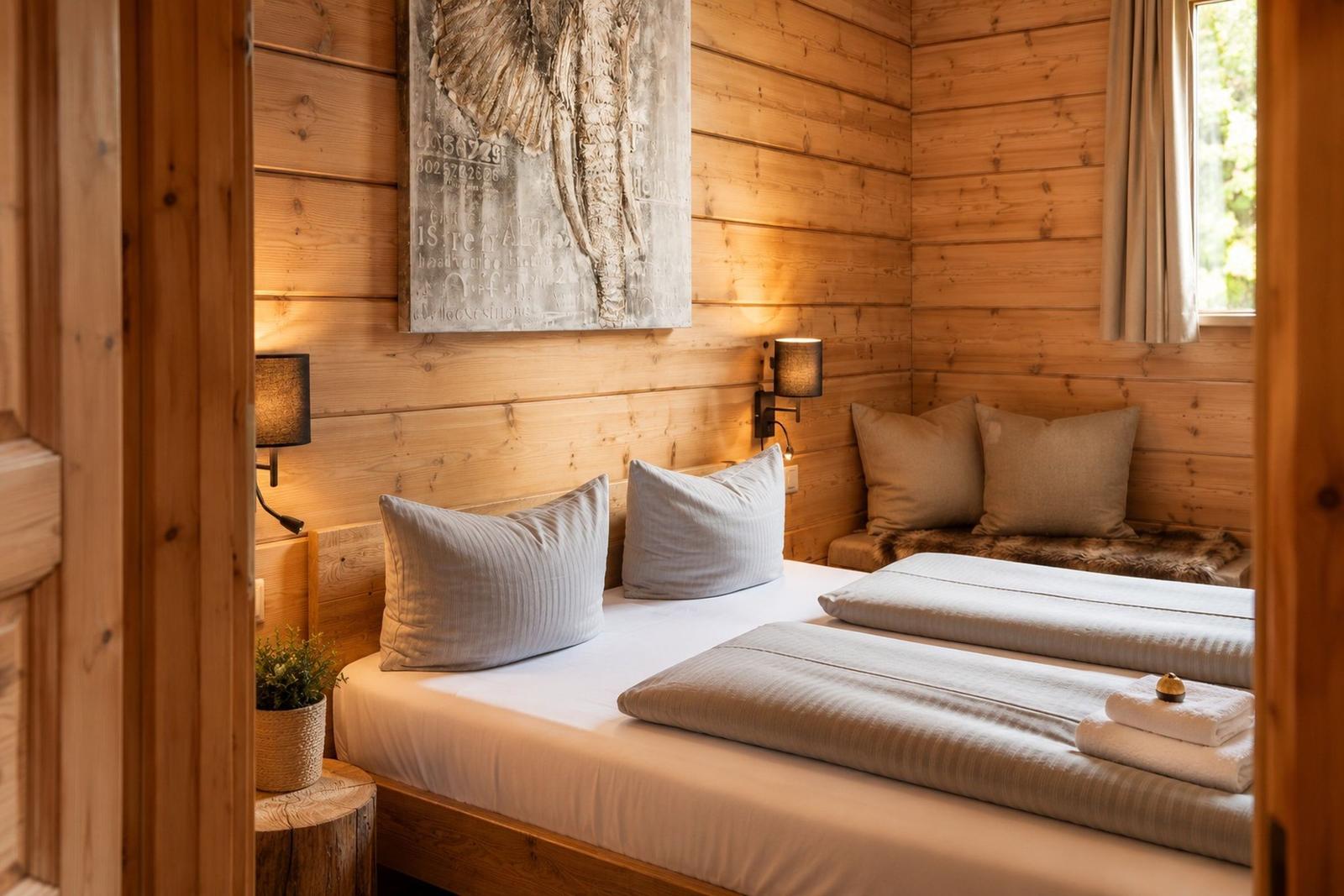 Schlafzimmer mit Holzwand, Bett, Kissen und Wandbild.