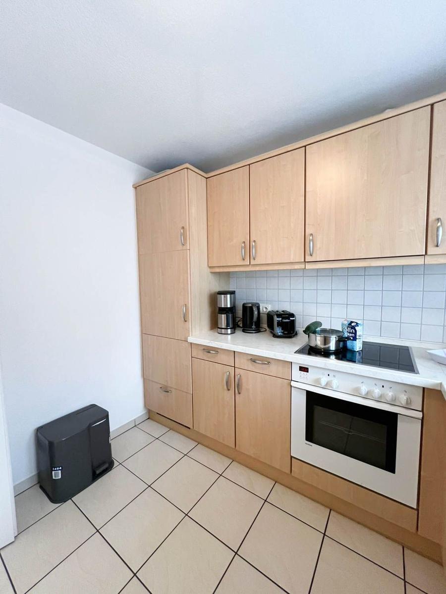 Küche mit Holzschränken, Herd und Kühlschrank