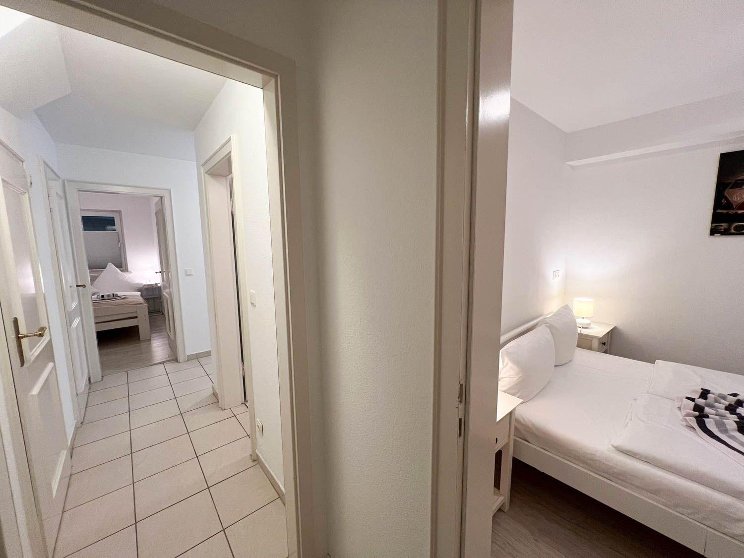 Zwei Schlafzimmer mit Betten und Nachttischen. Flur mit gefliestem Boden.