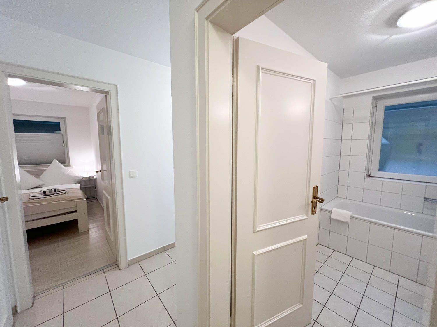 Badezimmer mit Badewanne und Tür zum Schlafzimmer mit Bett.
