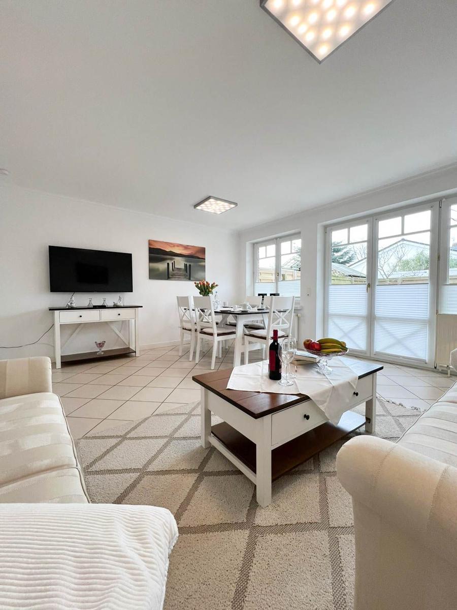 Wohn- und Essbereich mit Fernseher, Tisch, Stühlen und Glasfront zur Terrasse.