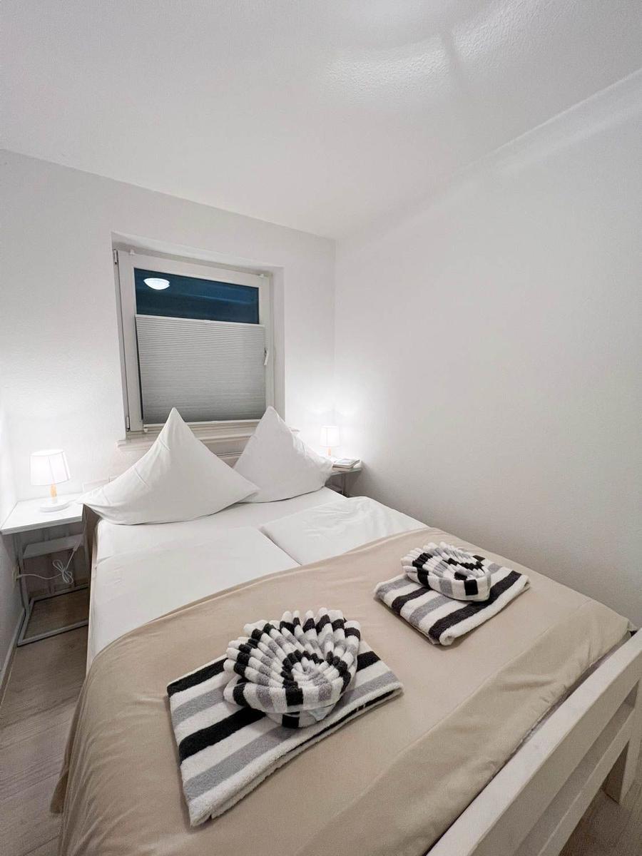 Ein Schlafzimmer mit Bett, zwei Nachttischen und einem Fenster mit Jalousie.
