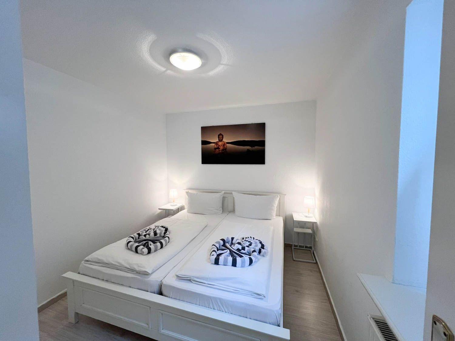 Ein Schlafzimmer mit einem Doppelbett, zwei Nachttischen und einer Wanddekoration.