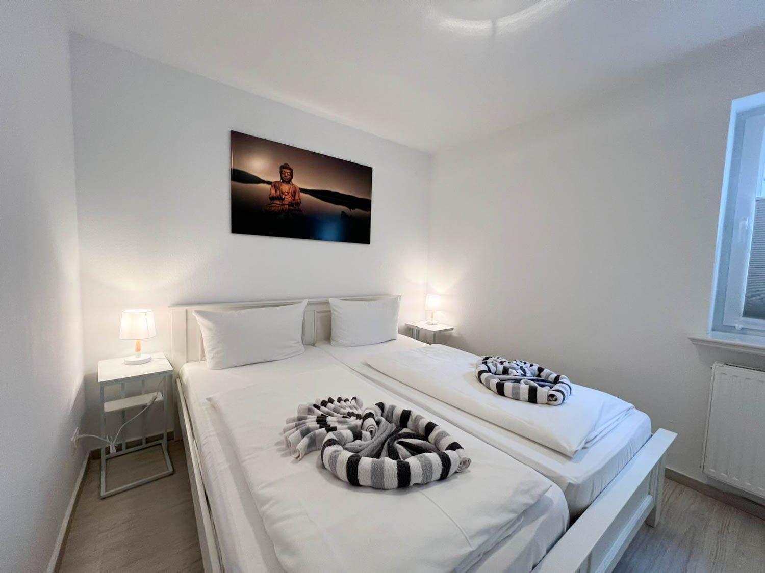 Zimmer mit Doppelbett, zwei Nachttischen und Wandbild.