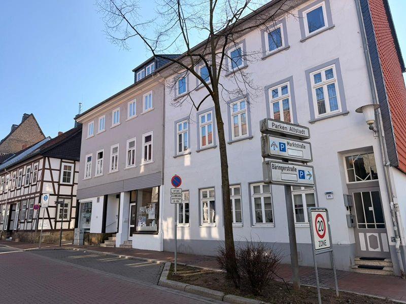 Fassade eines Mehrfamilienhauses mit Straßenschildern und Parkplatzanweisungen.
