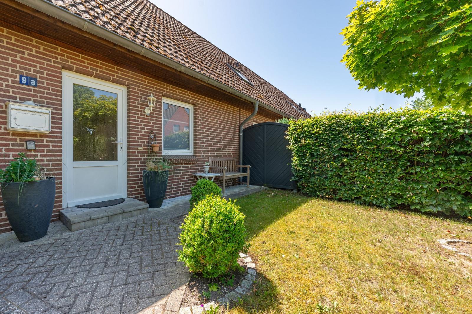 Haus mit Terrasse, Garten und Pflanzen. Eingangstür und Briefkasten sichtbar.