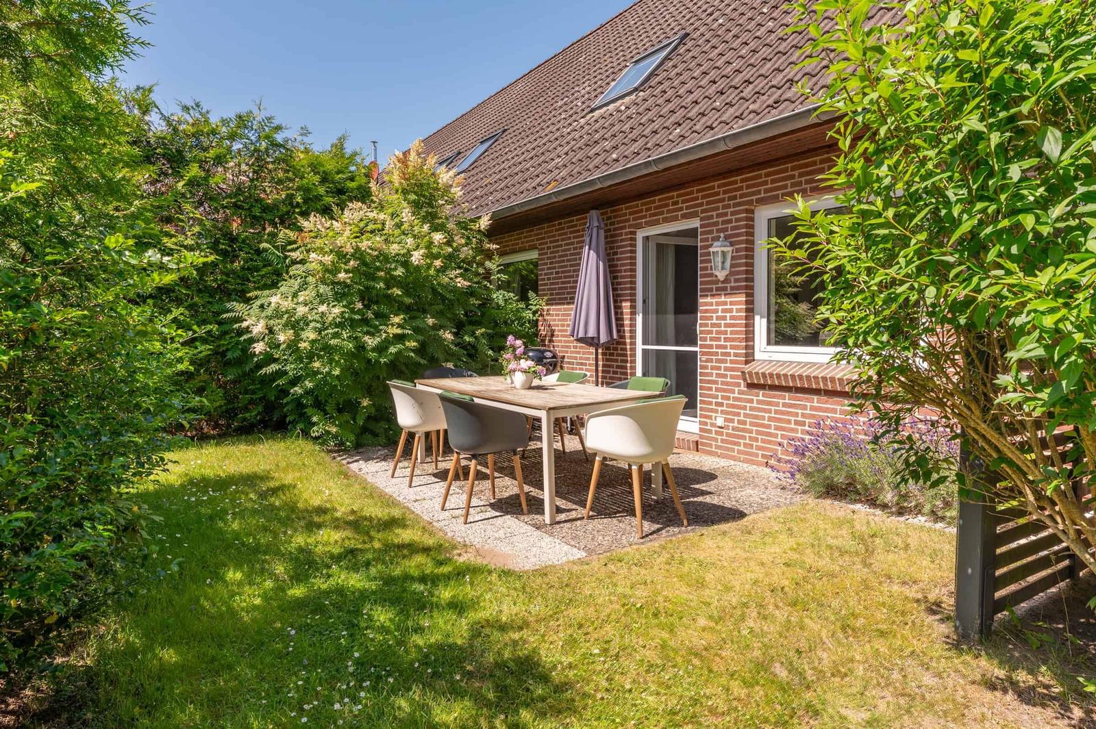 Hinterhof mit Sitzgruppe, Grill und Gartenhaus neben rotem Backsteinhaus.