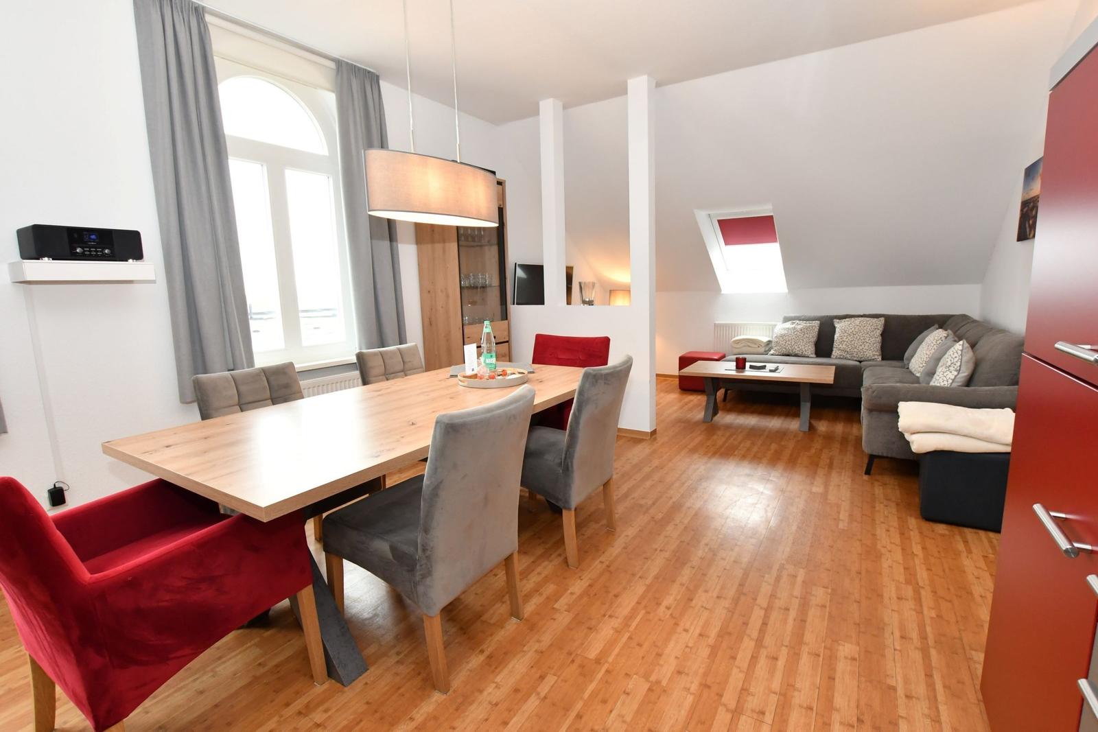 Essbereich mit Tisch und Stühlen. Wohnbereich mit Sofa und Couchtisch. Holzboden und Dachschräge.