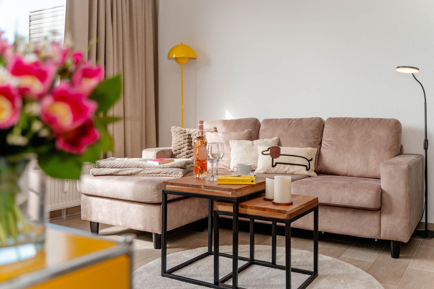 Ein Wohnzimmer mit einem Sofa, zwei Tischen und einer Stehlampe.